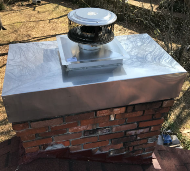 Chimney on roof with silver metal chase cover on top of vent