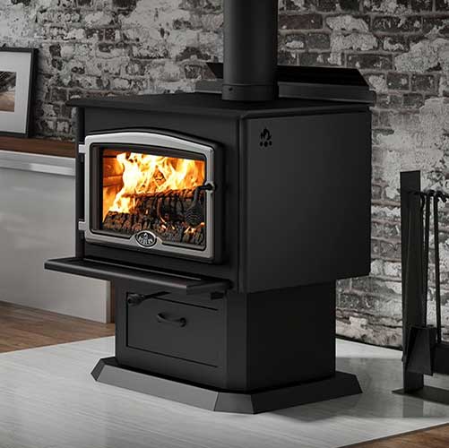 Stock photo of Osburn 2000 Wood Stove - Ashbusters Nashville Osburn 2000 Wood Stove - black with silver trim around the door and tools to the right. Old brick with splotches of concrete where it was not all removed.