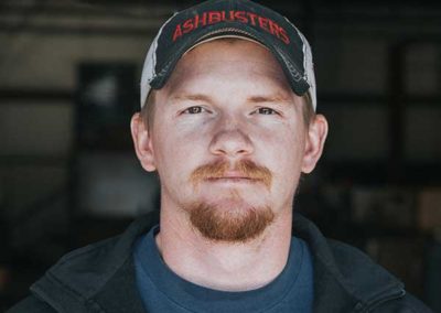 Bryson Woodall - He is wearing an Ashbusters hat with blondish reddish hair and eyebrows with bluish eyes. He has a red mustache and goatee.