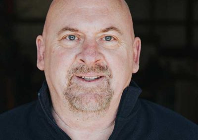 Kent Wessley - His head is shave. He has short brownish eyebrows with blue eyes. He has a reddish gray mustache and goatee.