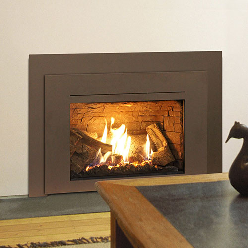 Brown gas fireplace insert with fire burning in it with corner of table showing a wooden animal