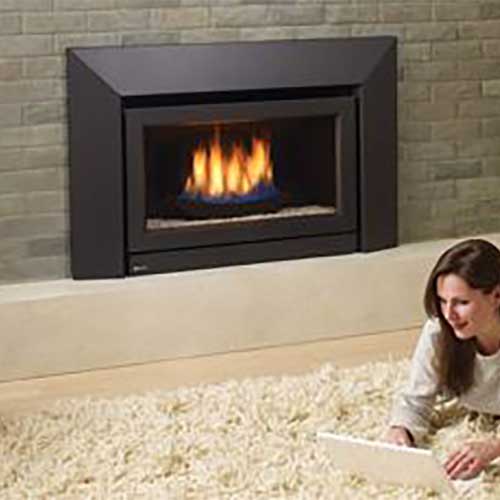 woman on laptop laying on white rug with fire burning in black gas insert